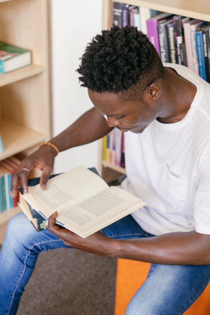 Young man reading a book in a library, ideal for education and learning concepts.
